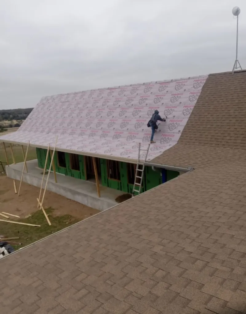 Worker preparing underlayment for a metal roof installation in Dripping Springs